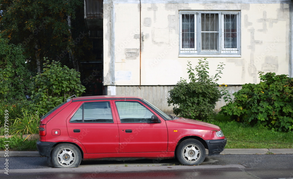An old red car with a flat tire stands near a residential building, Antonova-Ovseenko Street, St. Petersburg, Russia, September 2022 An old red car with a flat tire stands near a residential building, Antonova-Ovseenko Street, St. Petersburg, Russia, September 2022