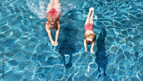 Happy family in swimming pool. Child with young woman swim, dive in pool with fun - jump deep down underwater. Healthy lifestyle, people water sport activity, swimming lessons on holidays with kids.