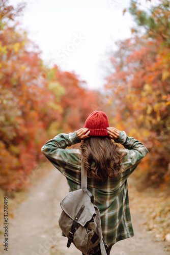 Young woman- tourist taking pictures in the autumn forest.  Rest  relaxation  tourism  nature  lifestyle concept.