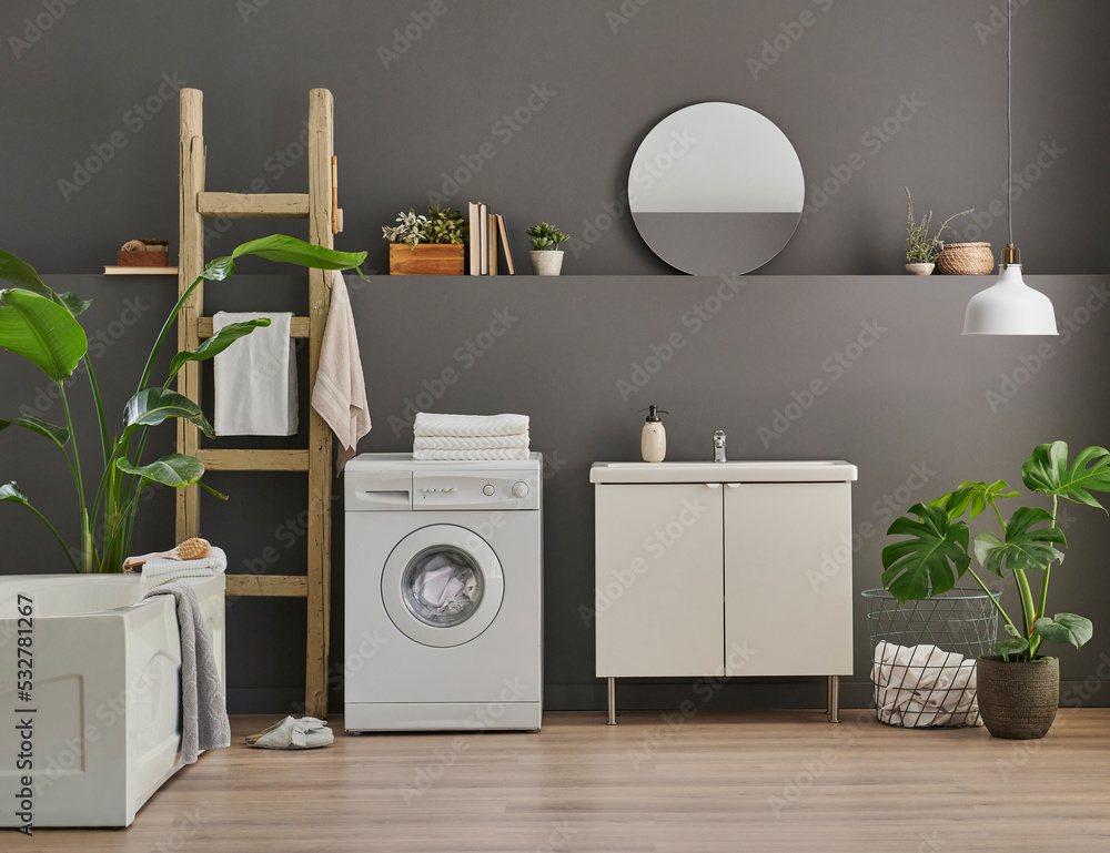 Modern bath room cabinet, sink, mirror and tub style grey wall background, vase of plant, laundry, towel and wooden stairs decorations. Modern bath room cabinet, sink, mirror and tub style grey wall background, vase of plant, laundry, towel and wooden stairs decorations.