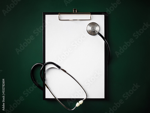 Blank clipboard with stethoscope on green background. Flat lay. photo