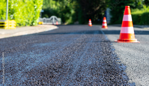 Fotografie Construction cones marking part of road with a layer of fresh asphalt