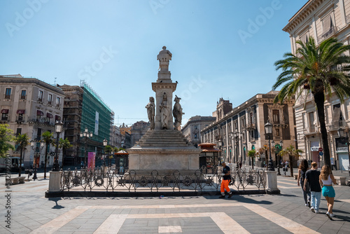 Catalina, Sicily, Italy. August 26, 2022. Monument of Vincenzo Bellini at Stesicoro Square. Historic buildings surrounding famous sculpture in city with blue sky in background during summer. photo