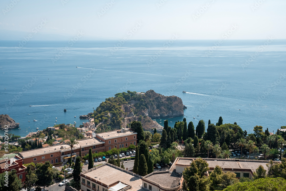 High angle view of houses at coastal city by Mediterranean sea. Scenic view of boats moving on blue ocean with sky in background. Beautiful scenery of urban landscape at island during summer.