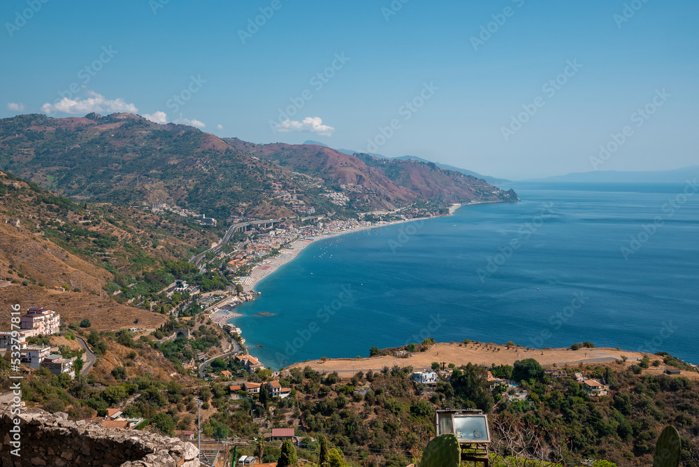 High angle view of scenic landscape at Mediterranean seacoast. Scenic seascape and coastal town with blue sky in background. Idyllic scenery of nature and urban land.