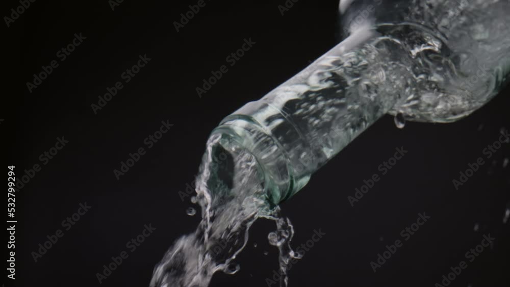 Fresh water splashing bottle in super slow motion closeup. Liquid stream flowing Fresh water splashing bottle in super slow motion closeup. Liquid stream flowing