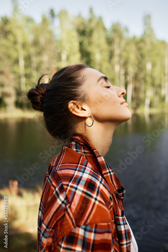 Fotografie Profile view of young brunette woman enjoying nature and making deep breath of f