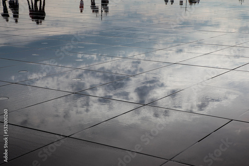 Reflections of people and clouds in an urban pool © Redzen