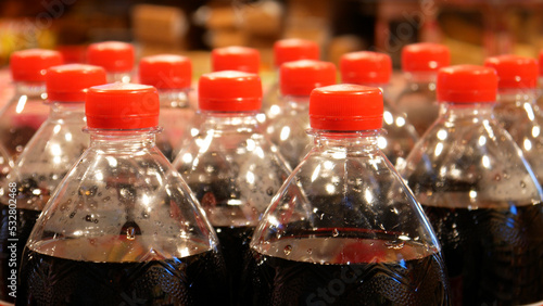 Close-up of many plastic bottles of cola with red caps
