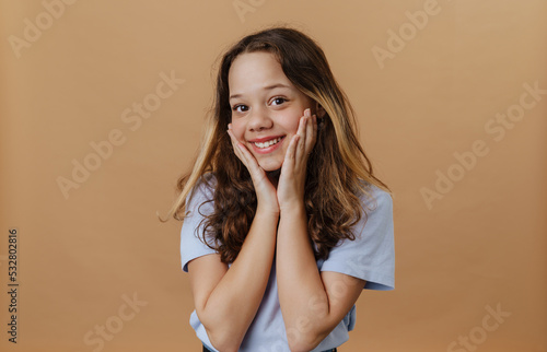 Young beautiful long-haired smiling girl in blue t-shirt holding cheeks