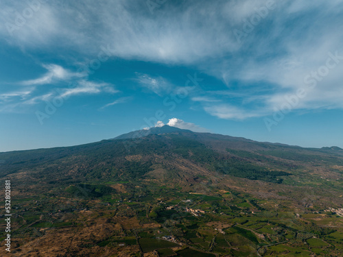 Idyllic view of clouds moving over famous Mount Etna. Active volcanic mountain with blue sky in background. Scenic view of tourist attraction amidst landscape during summer.