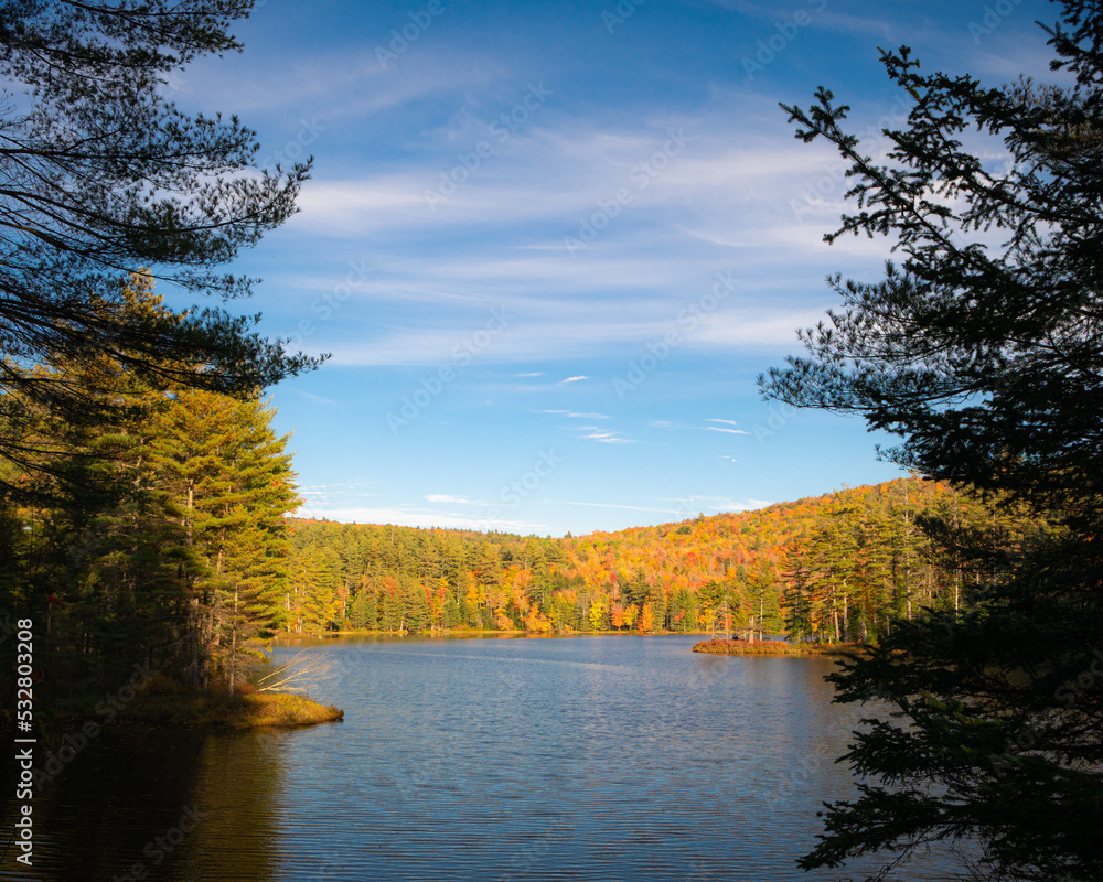 A beautiful autumn scene with a lake surrounded by a colorful forest in Vermont. A beautiful autumn scene with a lake surrounded by a colorful forest in Vermont.