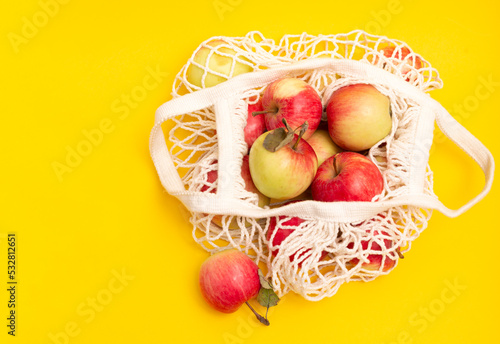 red apples in an eco-friendly bag on a yellow background