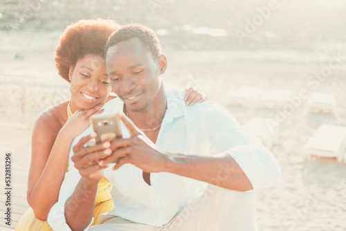Black couple young man and woman enjoy together connection technology using mobile phone and app. Happy modern people writing on smartphone in outdoor leisure activity together smiling and having fun © simona
