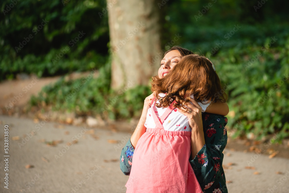 mother and daughter playing together in the park, happily surrounded by trees at the beginning of the autumn season. mother and daughter playing together in the park, happily surrounded by trees at the beginning of the autumn season.