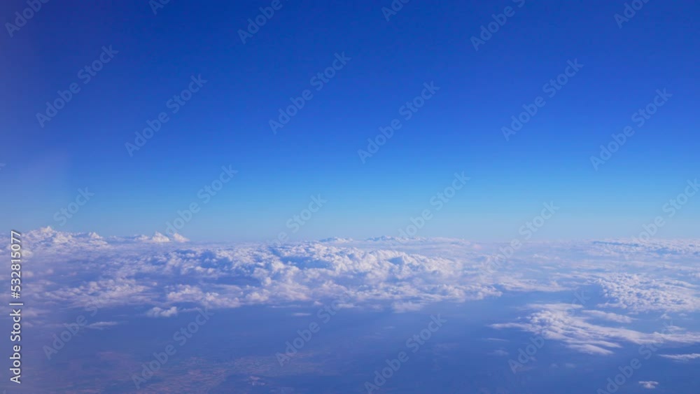 View from airplane window over white clouds and blue sky. Aerial view of city or town and nature from bird eye view. Beauty in nature landscape. Sun rays. Heaven. Altitude at level of stratosphere. View from airplane window over white clouds and blue sky. Aerial view of city or town and nature from bird eye view. Beauty in nature landscape. Sun rays. Heaven. Altitude at level of stratosphere.