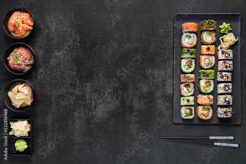 Sushi rolls with rice and fish, soy sauce on a dark stone background. Top view.
