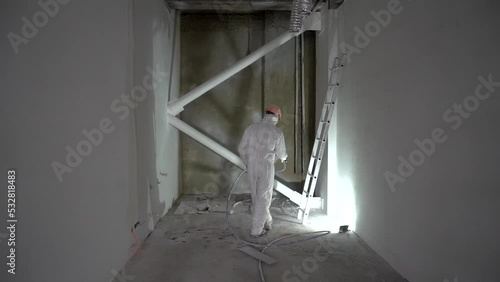 professional worker paints the walls with white paint spray gun. repair apartment