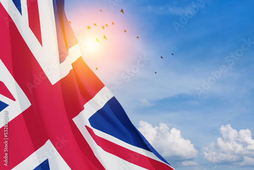 National flags of United Kingdom with flying birds on blue sky background. Background with place for your text. 3d rendering.