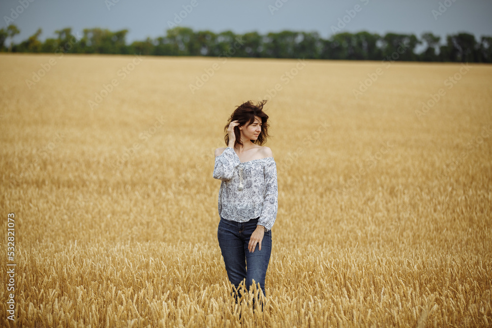 A girl in a field of yellow wheat on the background of a rainy sky A girl in a field of yellow wheat on the background of a rainy sky