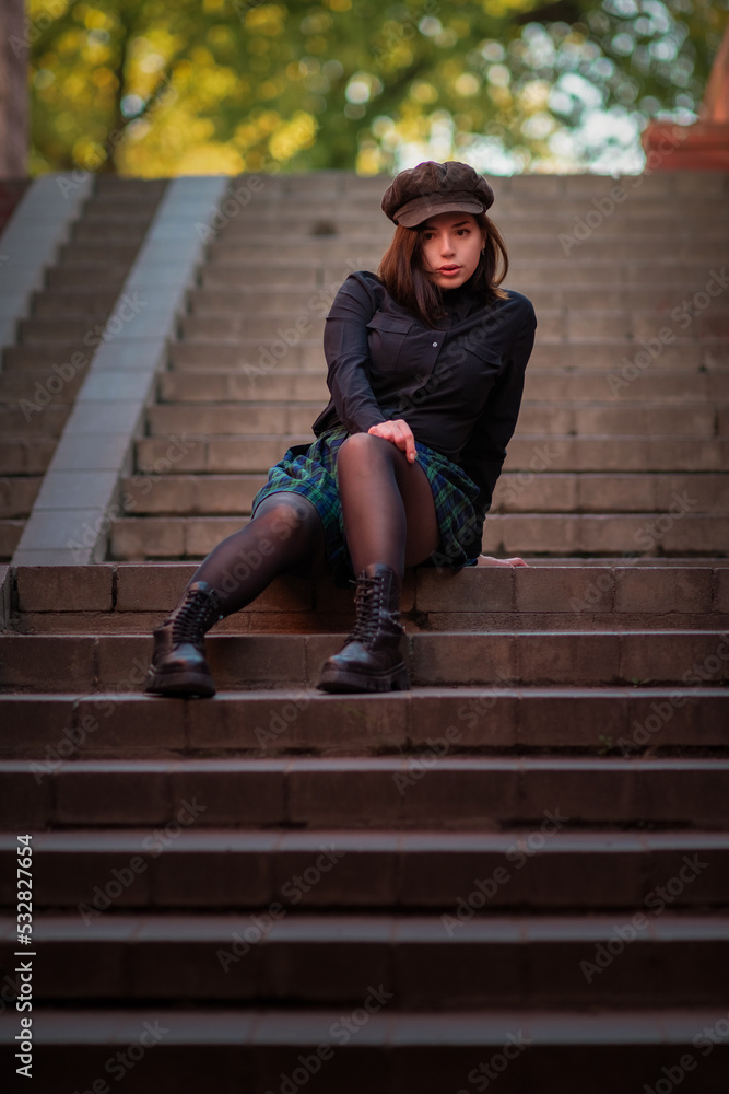 Portrait of a young beautiful girl sitting on the steps in the underpass.