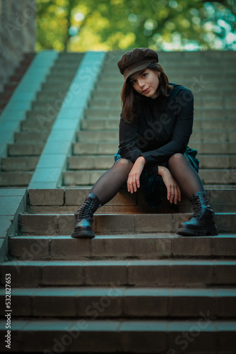 Portrait of a young beautiful girl sitting on the steps in the underpass.