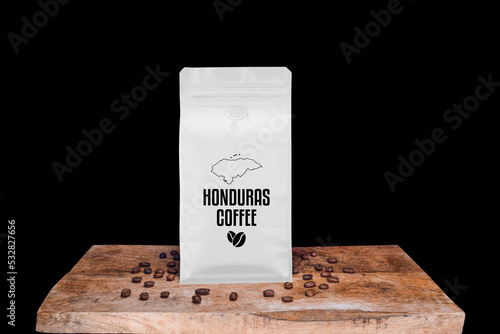Honduras coffee beans and white package on wooden board with black isolated background