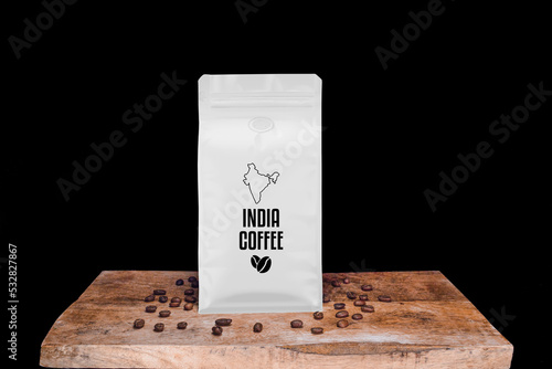 India coffee beans and white package on wooden board with black isolated background