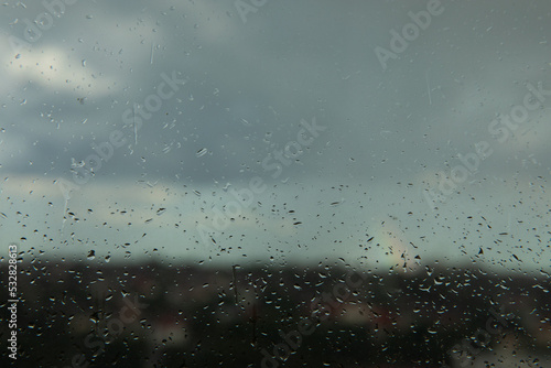 Glass with raindrops on the background of a thunderstorm. Raindrops on the background of the city.MOCKUP.Photo for design