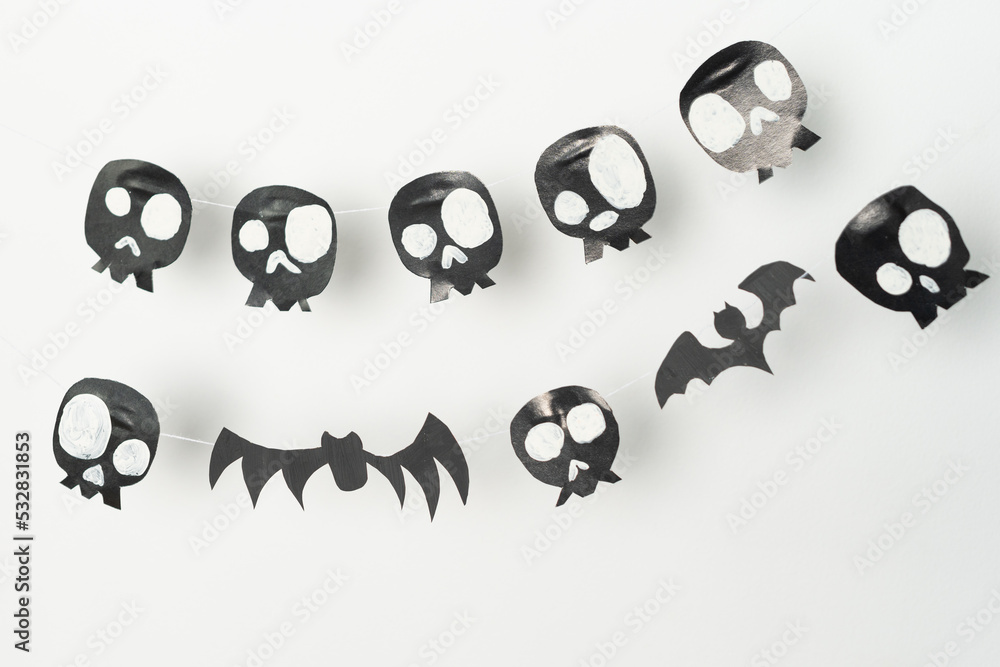 Skulls and flying bats cut out of black paper on a white background, preparation for Halloween. Skulls and flying bats cut out of black paper on a white background, preparation for Halloween.