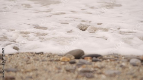 Detalle de la orilla de una playa pedregosa a cámara lenta
