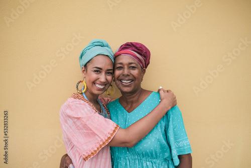 Happy african mother and adult daughter hugging each other while wearing traditional dress
