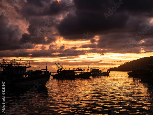 fishing boats at sunset with clouds in the sky