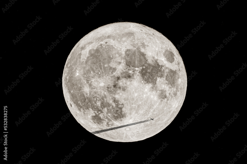Passenger plane and black chemtrails transiting in front of the Super Moon