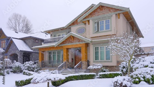 Establishing shot of two story stucco luxury house with big tree and nice landscape at winter snowfall in Vancouver, Canada, North America. Day time on December 2021. ProRes 422 HQ.