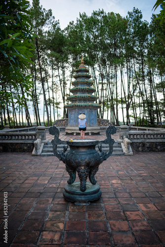 Mujer turista con sombrero vietnamita descubriendo templo budista en Thien Mu Pagoda photo