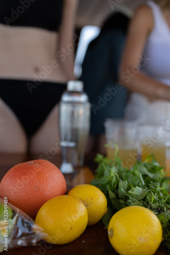 Young girls wearing bikini preparing cool cokctails. The focus is on her hand. No face in photo. Unrecognizable people.