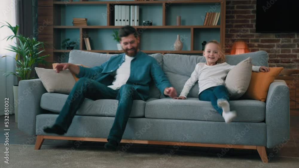 Happy caucasian young family daddy and child daughter jumping on soft couch for daytime break relaxation laugh enjoy relax rest on cozy couch testing comfort of sofa in furniture store room interior Happy caucasian young family daddy and child daughter jumping on soft couch for daytime break relaxation laugh enjoy relax rest on cozy couch testing comfort of sofa in furniture store room interior