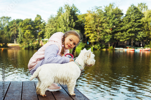 Wallpaper Mural A girl with pigtails plays with a small white dog and smiles happily. Torontodigital.ca