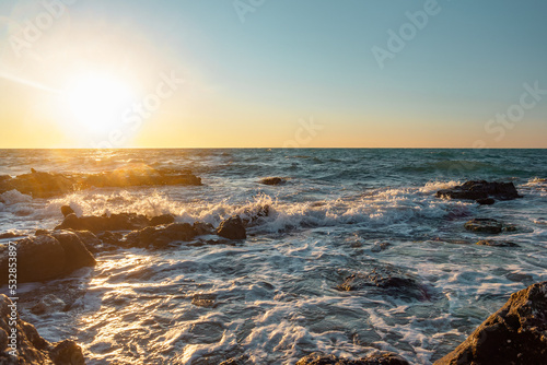 Fototapeta Naklejka Na Ścianę i Meble -  Beautiful seascape. Waves break on stone boulders on the seashore under the sunset sky