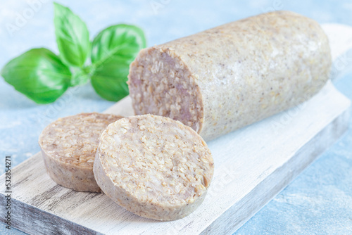 Traditional Irish white or oatmeal pudding sausage slices on a wooden board, horizontal
