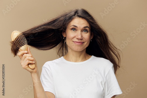 a sweet happy woman stands with a comb in her hair smiling looking at the camera