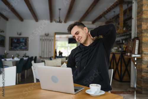 one man sit at the table at restaurant having neck pain or strain