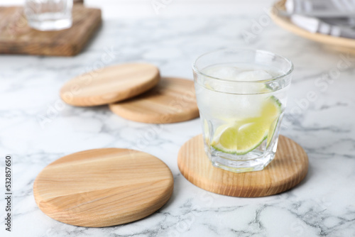 Glass of lemonade and stylish cup coasters on marble table, space for text