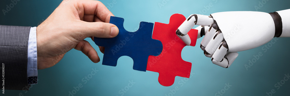 Businessperson And Robot Holding Jigsaw Puzzle Businessperson And Robot Holding Jigsaw Puzzle