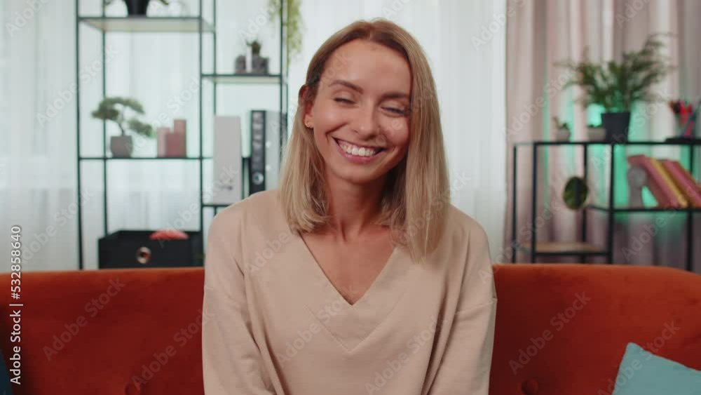Close-up portrait of happy smiling caucasian girl in shirt, looking at camera, celebrate good news. Young woman indoor isolated at home in living room sitting on orange couch. Female nature beauty Close-up portrait of happy smiling caucasian girl in shirt, looking at camera, celebrate good news. Young woman indoor isolated at home in living room sitting on orange couch. Female nature beauty