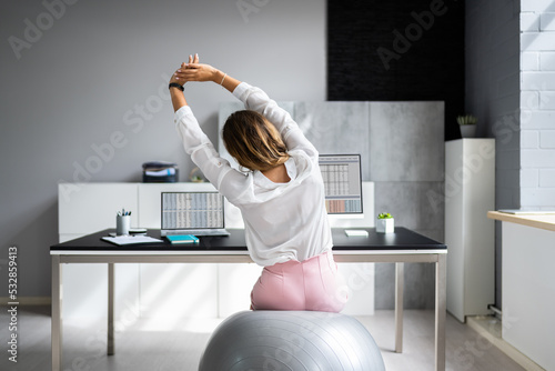 Fototapeta Naklejka Na Ścianę i Meble -  Employee Exercising On Ball In Office