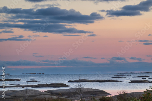 Looking out on Georgian Bay at sundown, over low humps of exposed granite rock to a horizon of blue clouds and a pink tinged sky. Shot on Whitefish Bay in September.