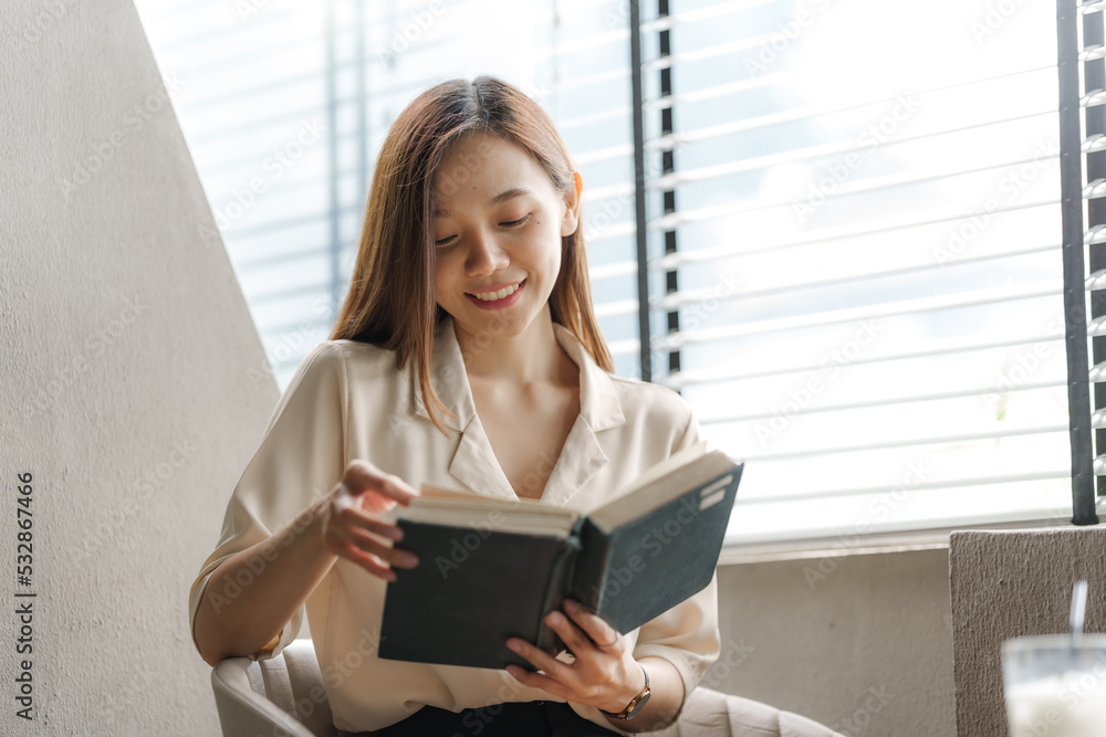 Portrait of confident pretty asian woman reading a book while relaxing. Portrait of confident pretty asian woman reading a book while relaxing.