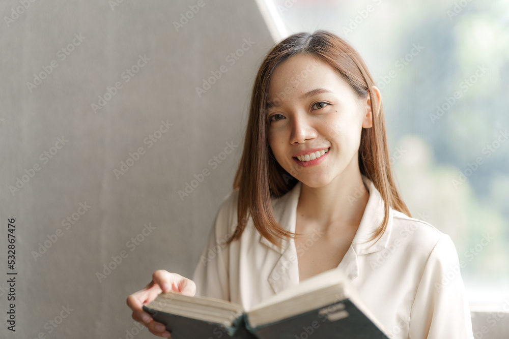 Portrait of confident pretty asian woman reading a book while relaxing.